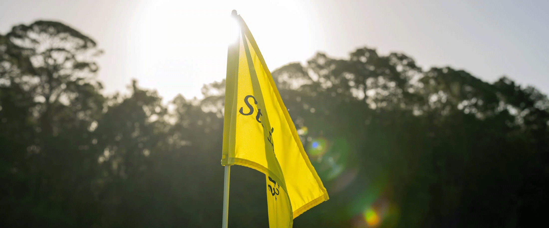 A yellow flag with the SJGC logo in front of the sunshine