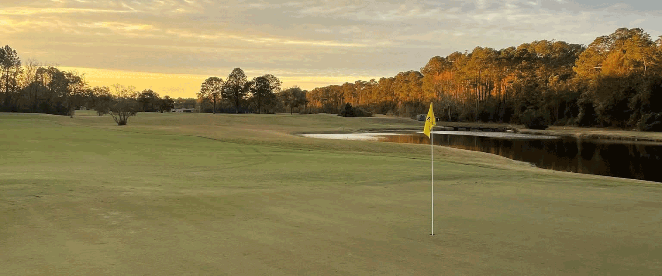 A yellow flag with the SJGC logo marks a hole on the golf course.